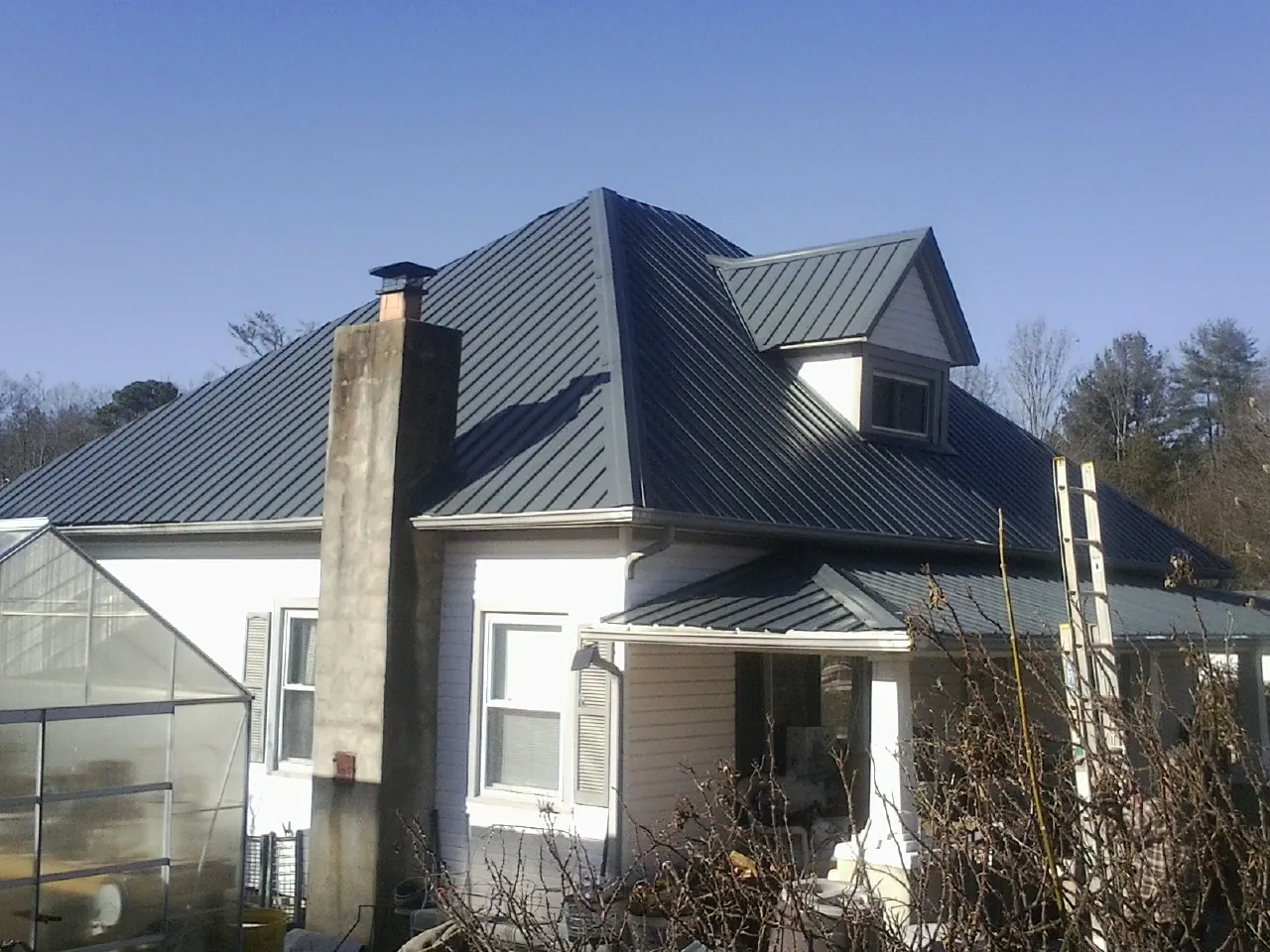 Dark blue standing seam metal roof on a white farmhouse with dormer — Slate & Tile Roof Repair by Roofing Brothers in Adena