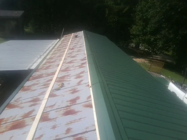 Old rusted panels beside newly installed green metal roofing — Wind Damage Roof Repair by Roofing Brothers in Adena