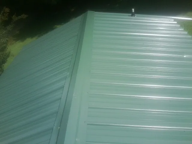 New green metal panels meeting at the ridge of a roof — Flat Roof Repair work by our crew in Adena