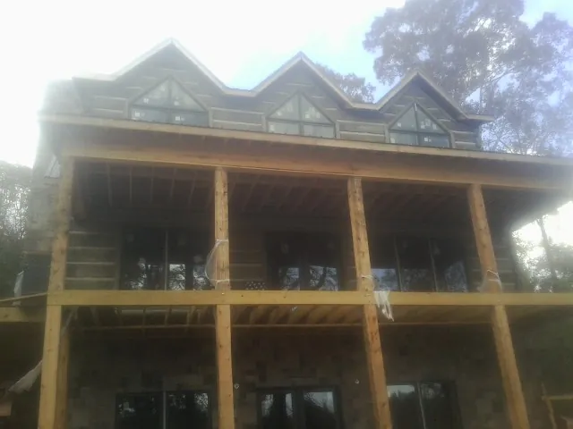 Dormers and porch framing on a large log home under construction — Roof Coating work by our crew in Adena