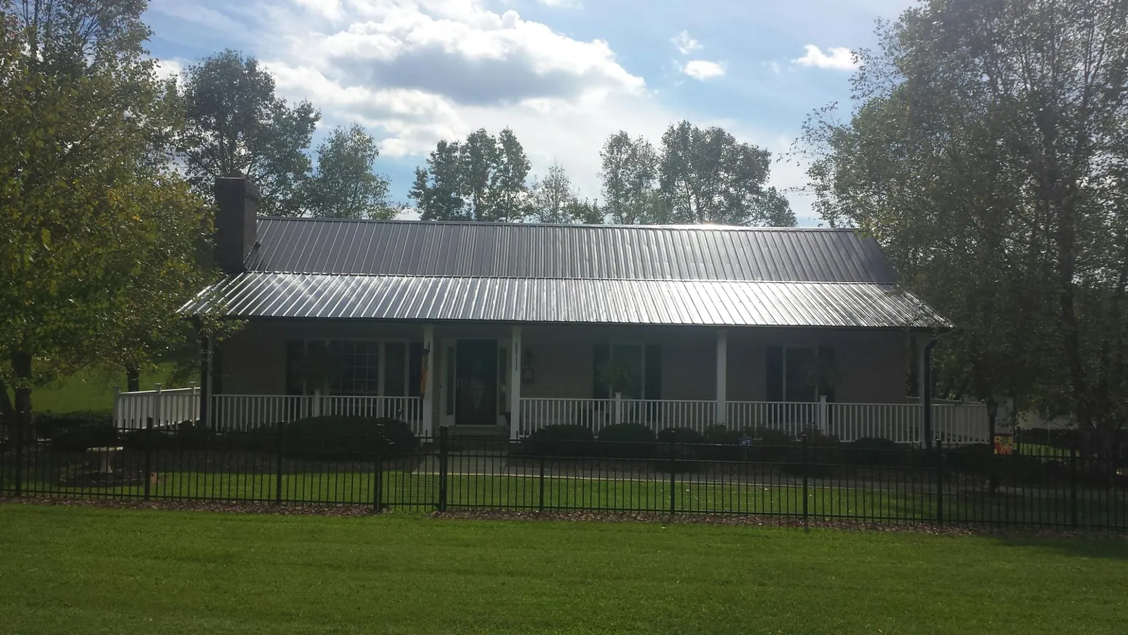 Gray metal roof on a brick ranch with a full width front porch — Gutter Guard Installation work by our crew in Adena