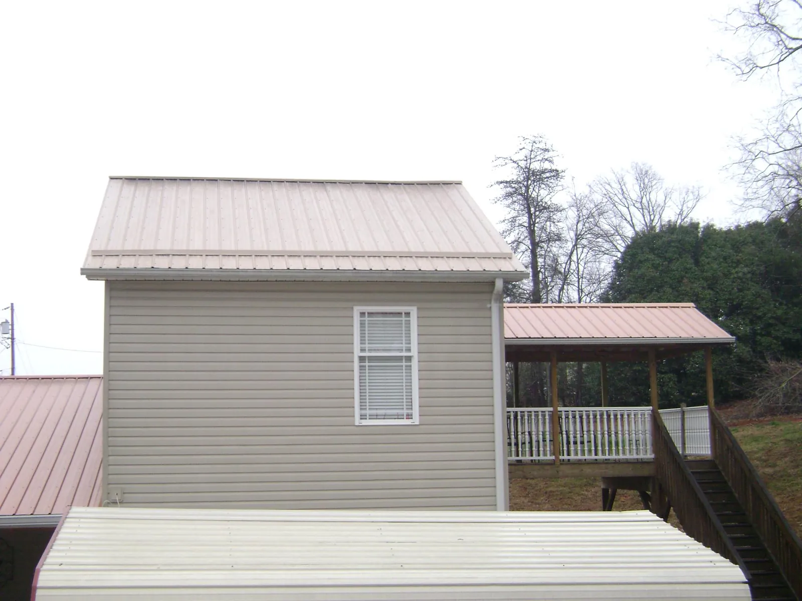Tan metal roofs on a two story addition and attached porch, from a Roof Replacement job in Adena