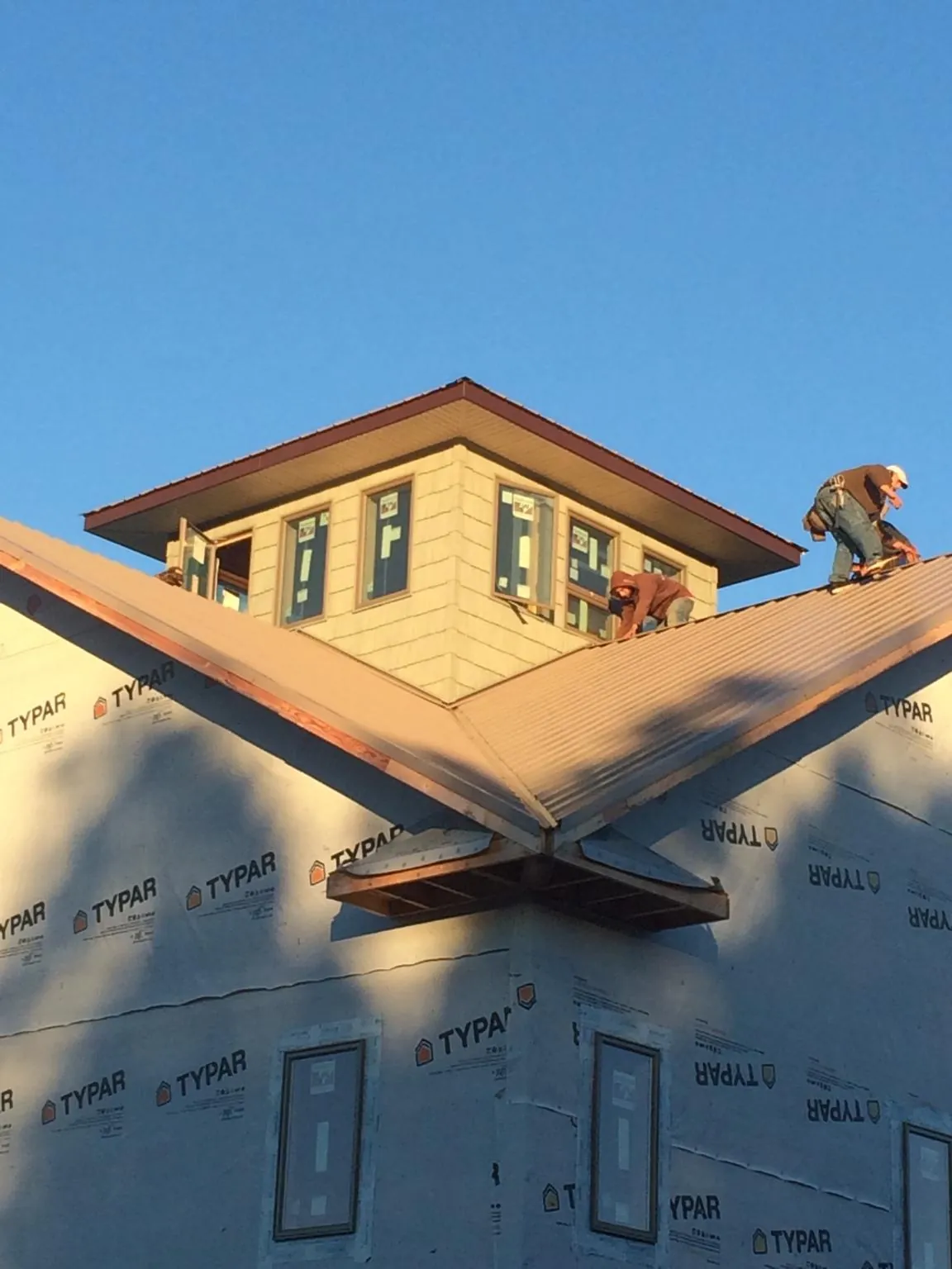 Roofers working around a rooftop cupola on a new metal roof at sunset — Roof Waterproofing in Adena by Roofing Brothers